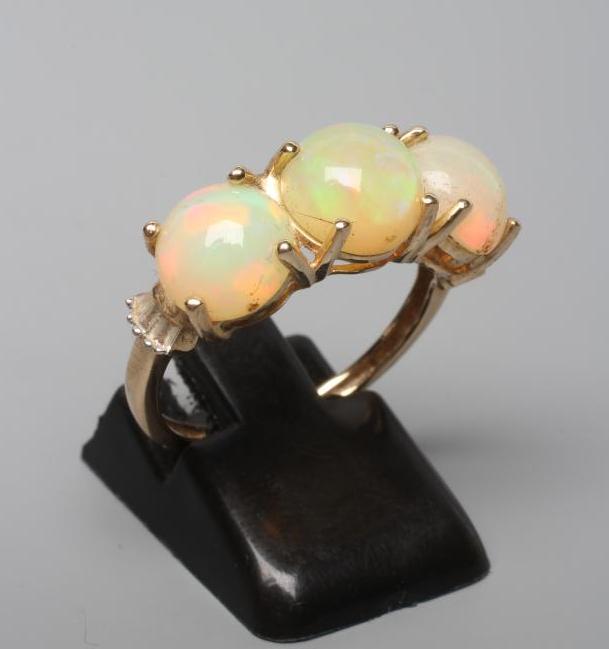 A THREE STONE OPAL RING, the round cabochon polished stones claw set to a plain 14ct gold shank, Image