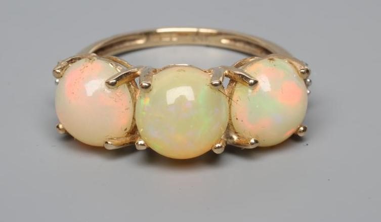 A THREE STONE OPAL RING, the round cabochon polished stones claw set to a plain 14ct gold shank, Image