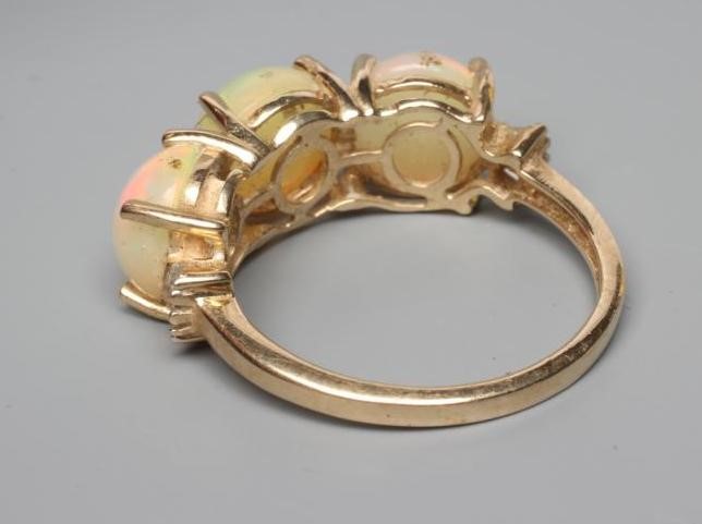 A THREE STONE OPAL RING, the round cabochon polished stones claw set to a plain 14ct gold shank, Image