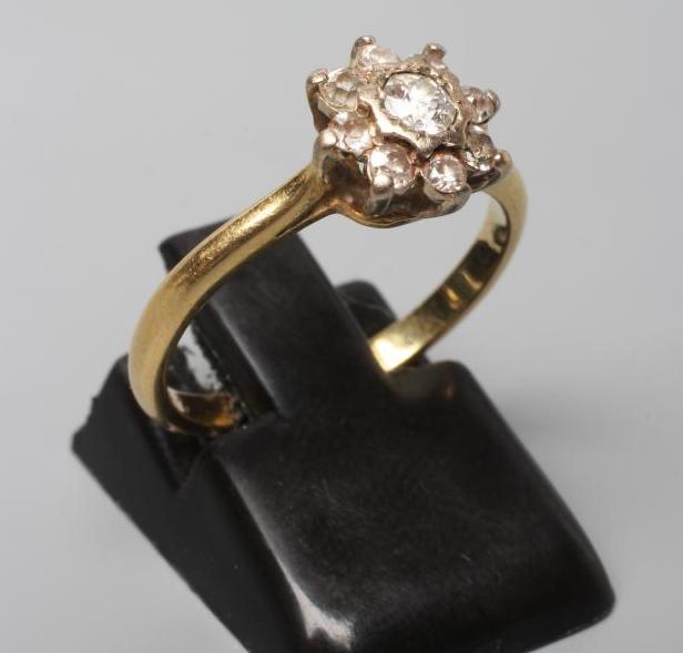 A NINE STONE DIAMOND CLUSTER RING, the round brilliant cut stones point set to a plain 18ct gold Image