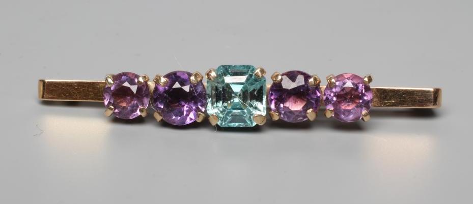 AN EDWARDIAN BROOCH centred by a cushion cut blue zircon flanked by two pairs of graduated amethysts Image