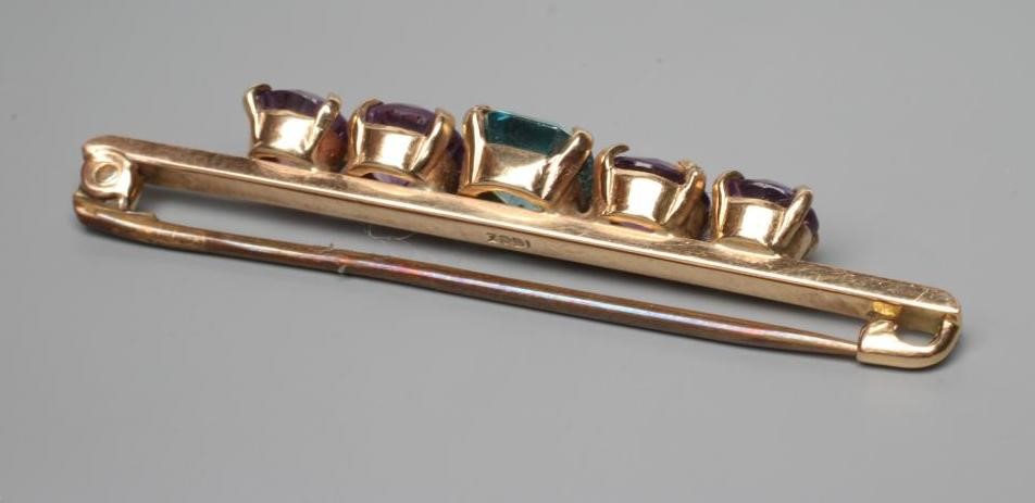 AN EDWARDIAN BROOCH centred by a cushion cut blue zircon flanked by two pairs of graduated amethysts Image