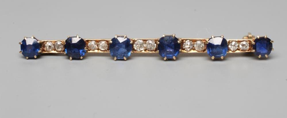 A SAPPHIRE AND DIAMOND BAR BROOCH, the six graduated circular facet cut sapphires claw set to a Image