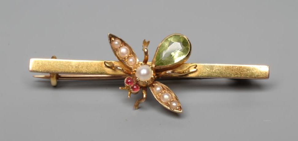 AN EDWARDIAN NOVELTY BAR BROOCH centred by an insect with seed pearl wings and head, ruby cabochon Image