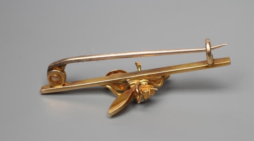 AN EDWARDIAN NOVELTY BAR BROOCH centred by an insect with seed pearl wings and head, ruby cabochon Image