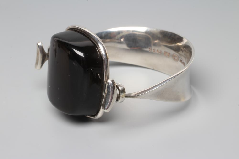 A GEORG JENSEN SILVER BANGLE designed by Vivianna Torun Bulow-Hube, the tension clamp centred by a Image