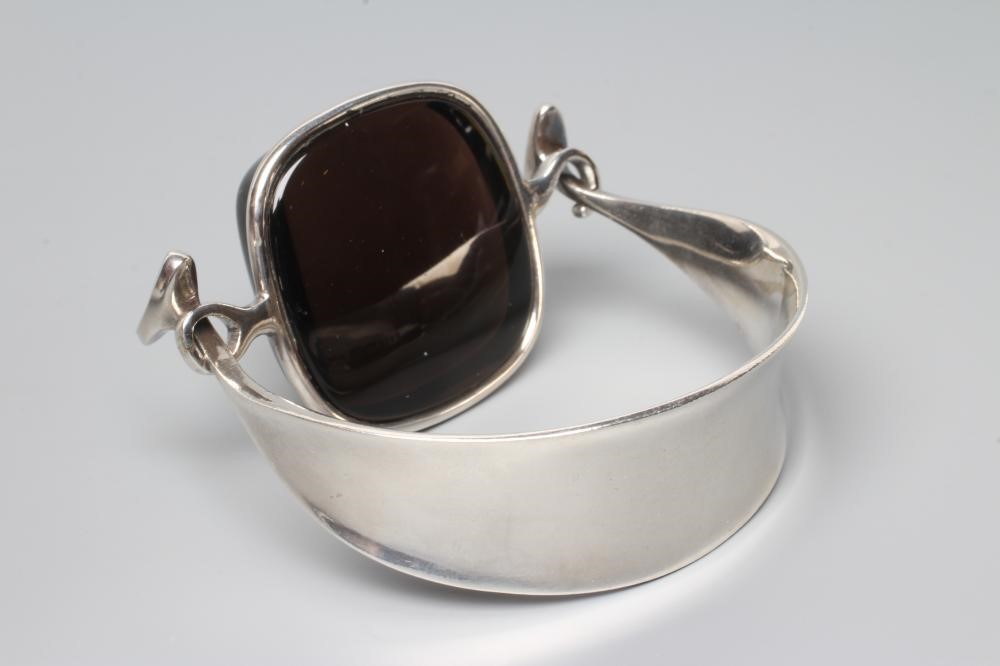 A GEORG JENSEN SILVER BANGLE designed by Vivianna Torun Bulow-Hube, the tension clamp centred by a Image