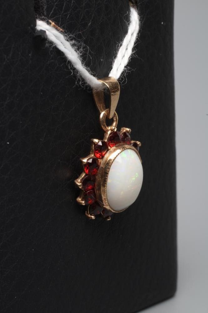 AN OPAL AND GARNET CLUSTER PENDANT, the oval cabochon polished opal collet set to a border of small Image