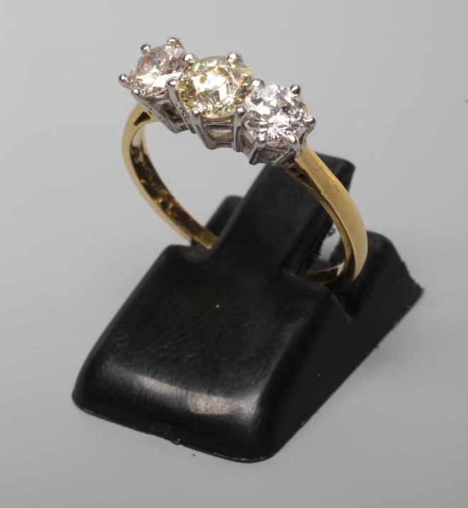 A THREE STONE DIAMOND RING, the central old cut stone flanked by two similar smaller stones Image