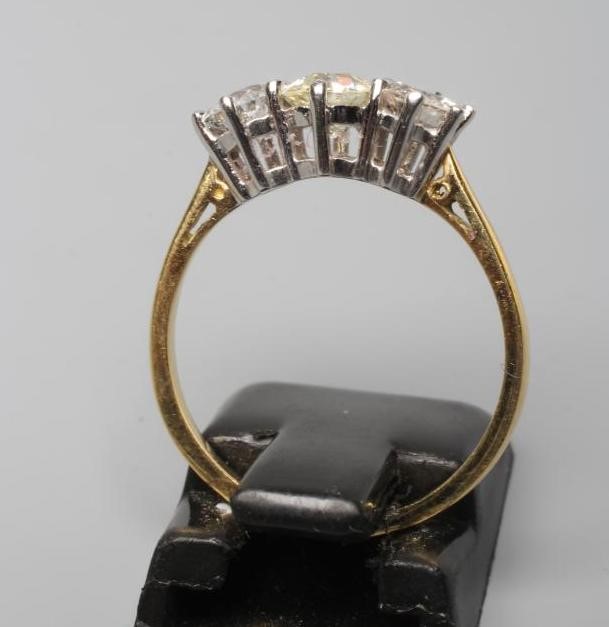 A THREE STONE DIAMOND RING, the central old cut stone flanked by two similar smaller stones Image