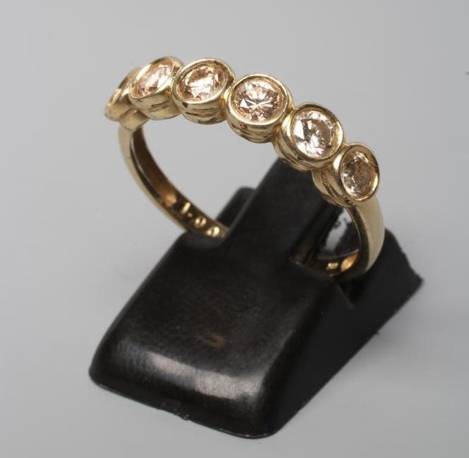 A SIX STONE DIAMOND RING, the round brilliant cut stones open back collet set to a plain shank, Image