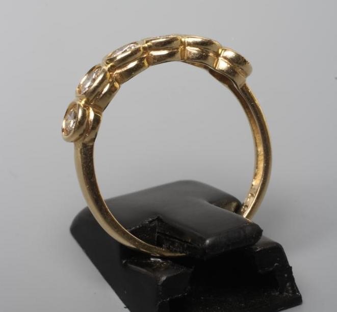 A SIX STONE DIAMOND RING, the round brilliant cut stones open back collet set to a plain shank, Image