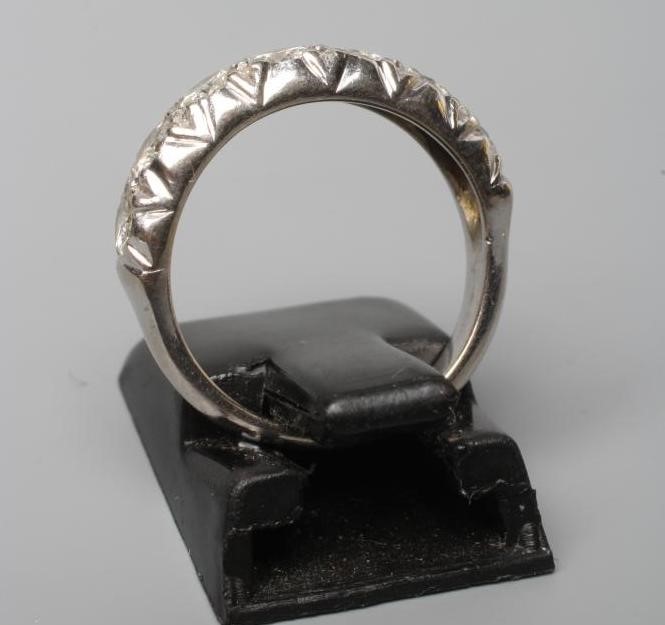 A SEVEN STONE DIAMOND HALF HOOP RING, the round brilliants line set to a plain white shank stamped Image