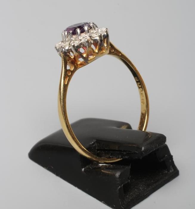 AN AMETHYST AND DIAMOND CLUSTER RING, the oval facet cut amethyst claw set to a border of small Image