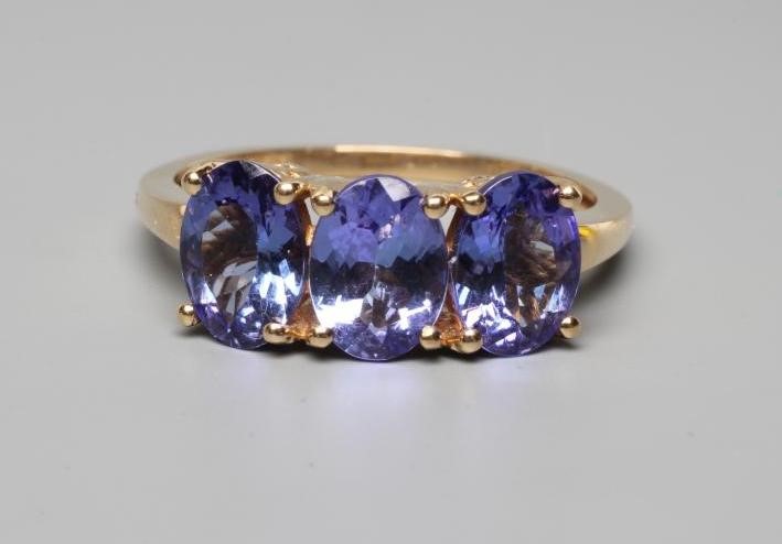 A THREE STONE TANZANITE RING, the oval facet cut stones claw set to a plain shank, stamped 14k, 585, Image