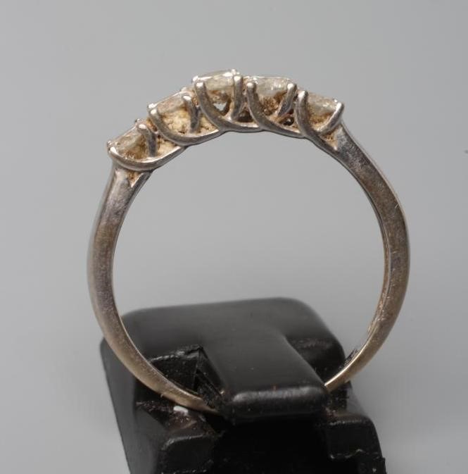 A FIVE STONE DIAMOND RING, the round brilliant cut stones point set to a plain white shank, stamped Image