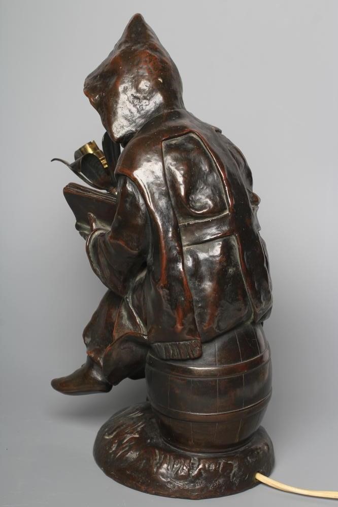 A BRONZED METAL FIGURAL TABLE LAMP, 20th century, modelled as a hooded child seated on a barrel, Image