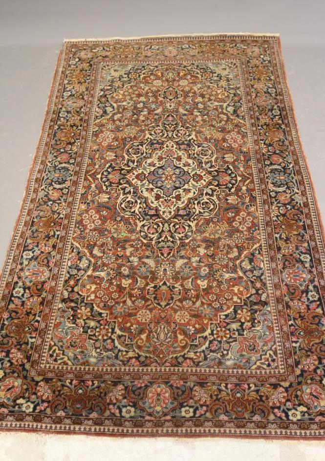 A PERSIAN RUG, early 20th century, the red floral field with central navy blue gul, navy blue main Image