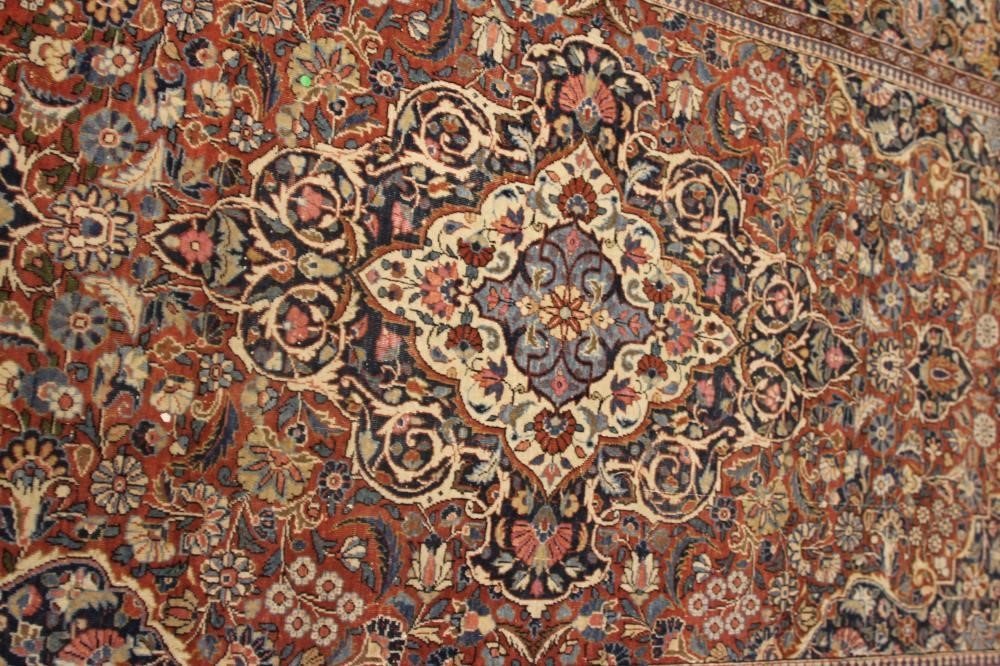 A PERSIAN RUG, early 20th century, the red floral field with central navy blue gul, navy blue main Image
