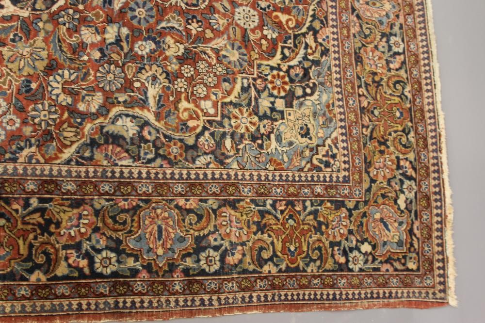 A PERSIAN RUG, early 20th century, the red floral field with central navy blue gul, navy blue main Image