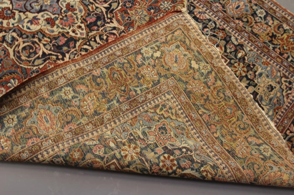 A PERSIAN RUG, early 20th century, the red floral field with central navy blue gul, navy blue main Image
