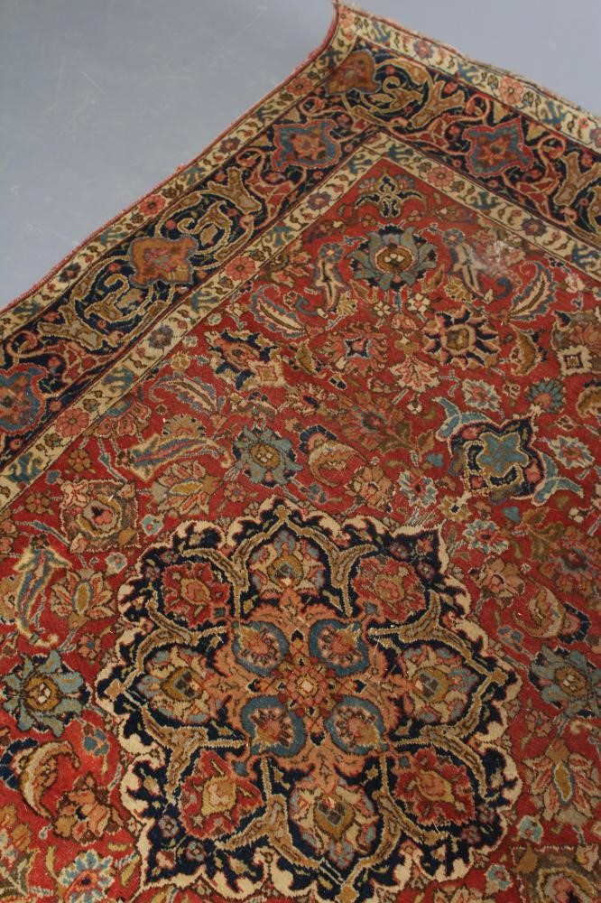 A PERSIAN RUG, early 20th century, the red floral field with central navy blue gul, navy blue main Image