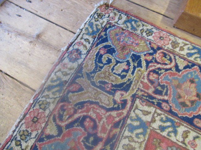 A PERSIAN RUG, early 20th century, the red floral field with central navy blue gul, navy blue main Image