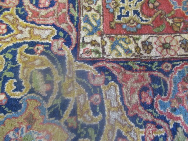 A PERSIAN RUG, early 20th century, the red floral field with central navy blue gul, navy blue main Image