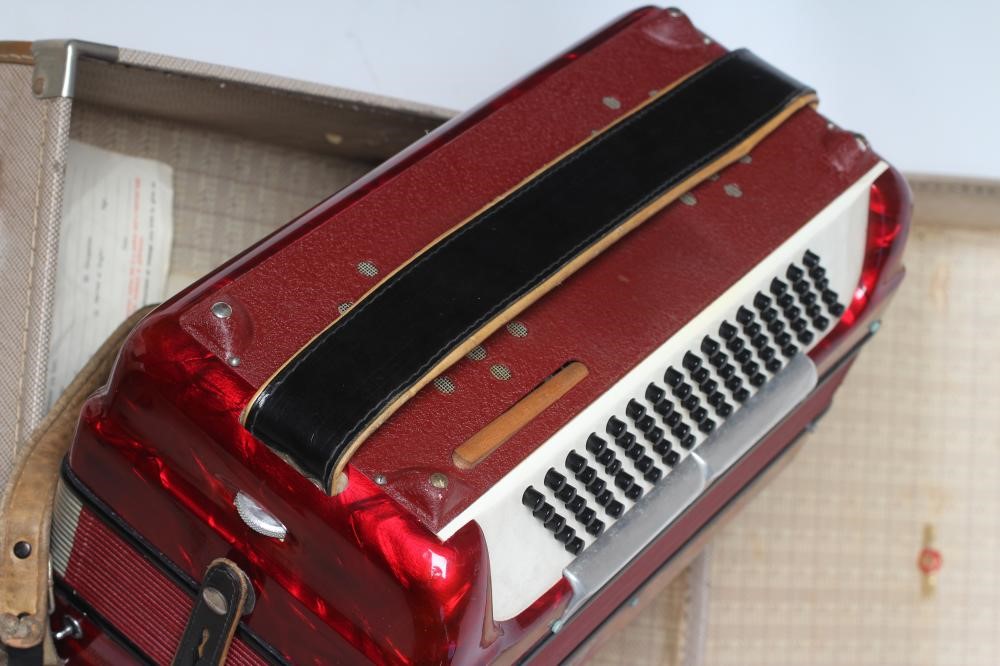A PAOLO SOPRANI BUTTON ACCORDIAN with red marbled effect case, leather strapping and hard case (Est. Image