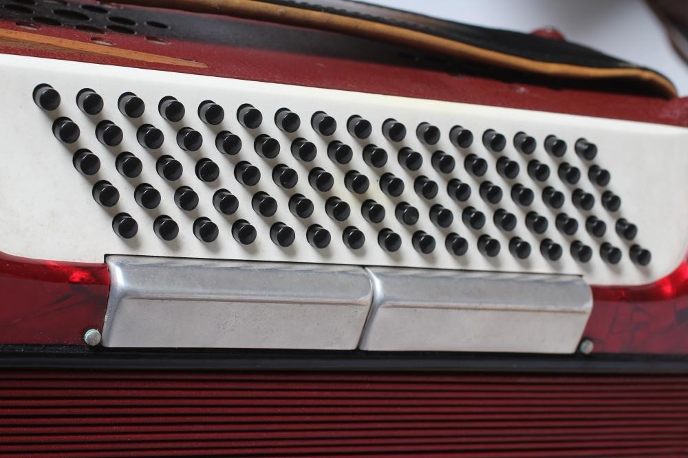 A PAOLO SOPRANI BUTTON ACCORDIAN with red marbled effect case, leather strapping and hard case (Est. Image