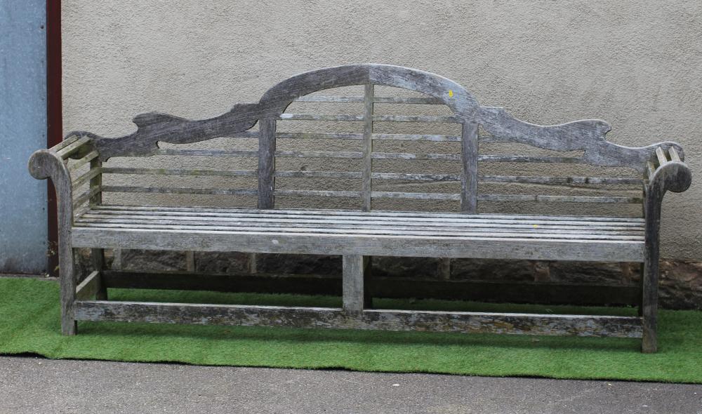 A LUTYENS STYLE SLATTED TEAK GARDEN BENCH with arched back and scrolled arms, raised on square Image