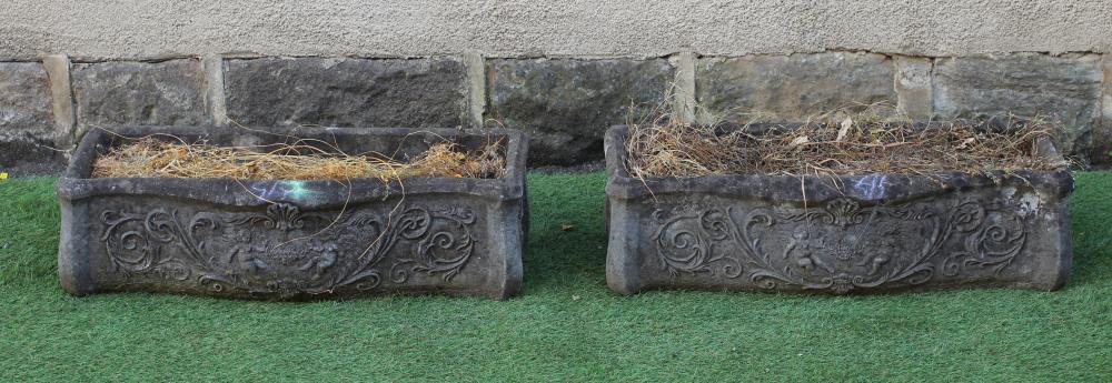 A PAIR OF CAST STONE PLANTERS of oblong serpentine form moulded with foliate scrolls centred by a Image