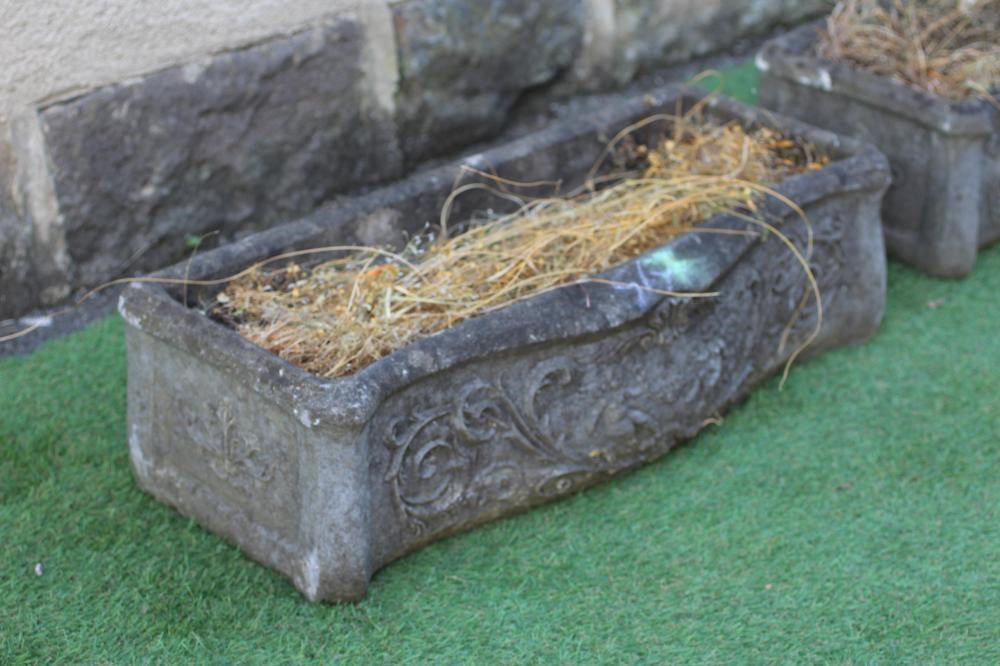 A PAIR OF CAST STONE PLANTERS of oblong serpentine form moulded with foliate scrolls centred by a Image