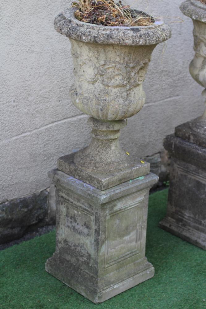 A PAIR OF CAST STONE URNS of half fluted campana form with ovolu moulded rim Image