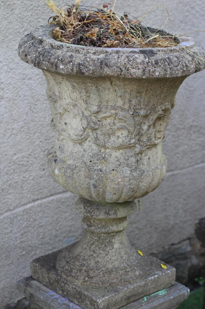 A PAIR OF CAST STONE URNS of half fluted campana form with ovolu moulded rim Image