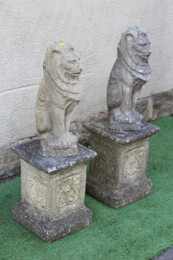 A PAIR OF CAST STONE LIONS SEJANT, raised on associated flower moulded stepped square plinth, 12" x Image