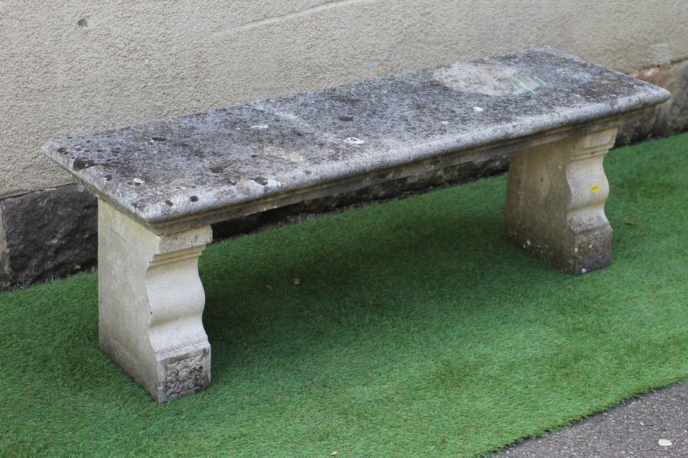A CAST STONE BENCH, the moulded edged oblong seat raised on flower moulded square section end Image