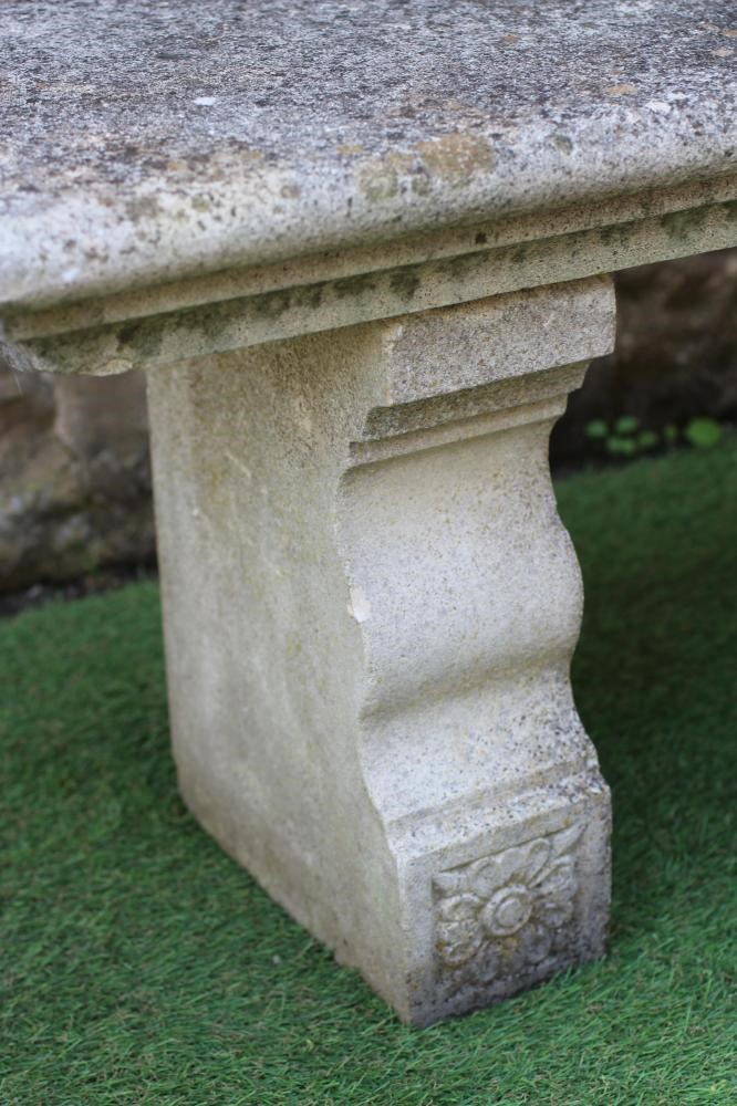 A CAST STONE BENCH, the moulded edged oblong seat raised on flower moulded square section end Image