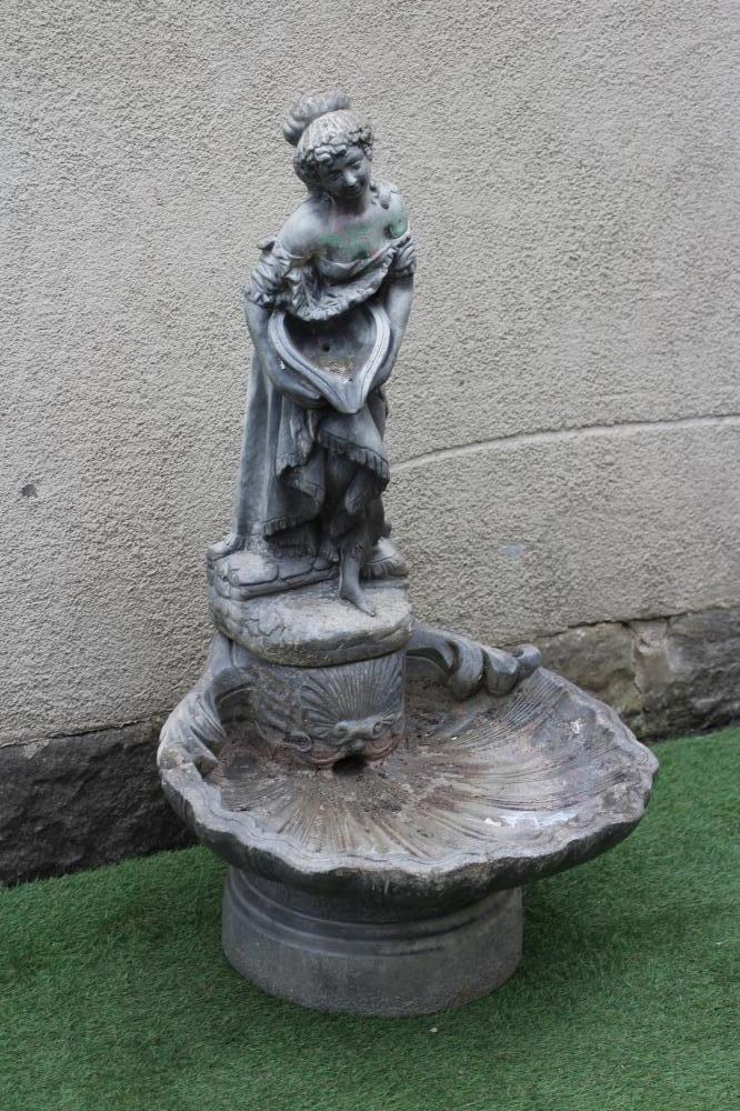 A CAST STONE FOUNTAIN modelled as an escallop shell surmounted by a semi clad maiden holding a water Image