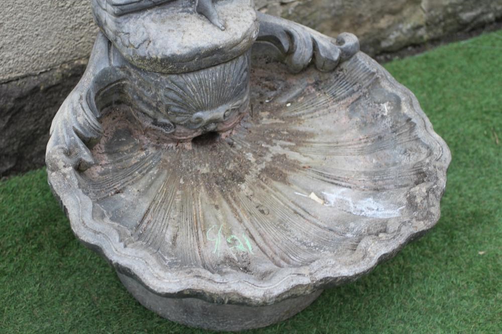 A CAST STONE FOUNTAIN modelled as an escallop shell surmounted by a semi clad maiden holding a water Image