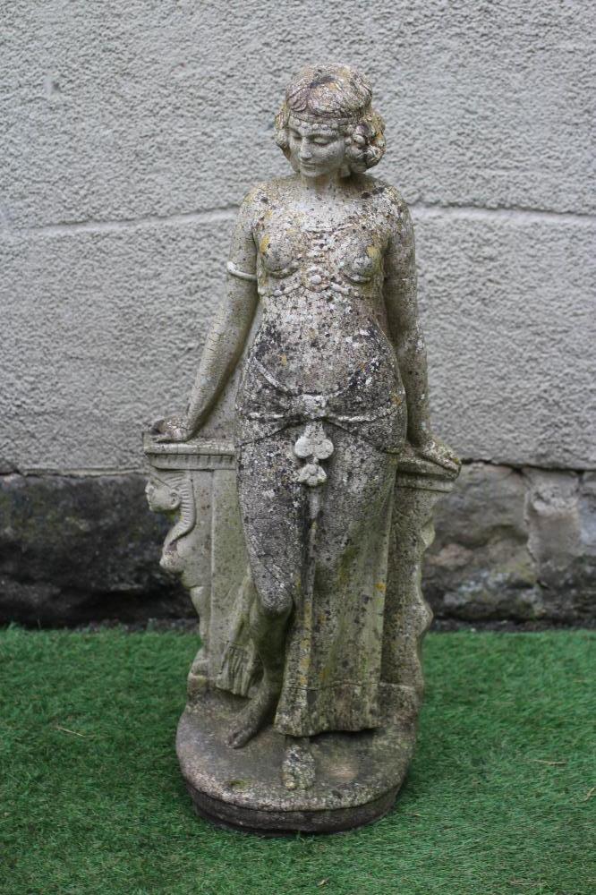 A CAST STONE FIGURE OF AN ODALESQUE modelled standing and leaning against a plinth, 30 3/4" high Image