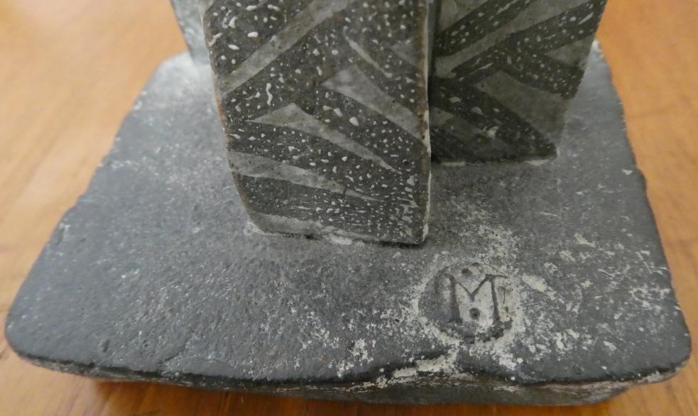 JOHN MALTBY (1936-2000) - a matt grey stoneware sculpture of two figures standing before a cut slab Image