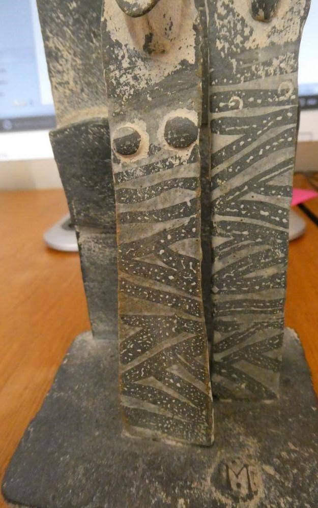 JOHN MALTBY (1936-2000) - a matt grey stoneware sculpture of two figures standing before a cut slab Image