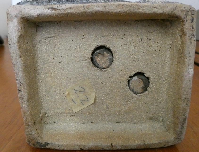 JOHN MALTBY (1936-2000) - a matt grey stoneware sculpture of two figures standing before a cut slab Image