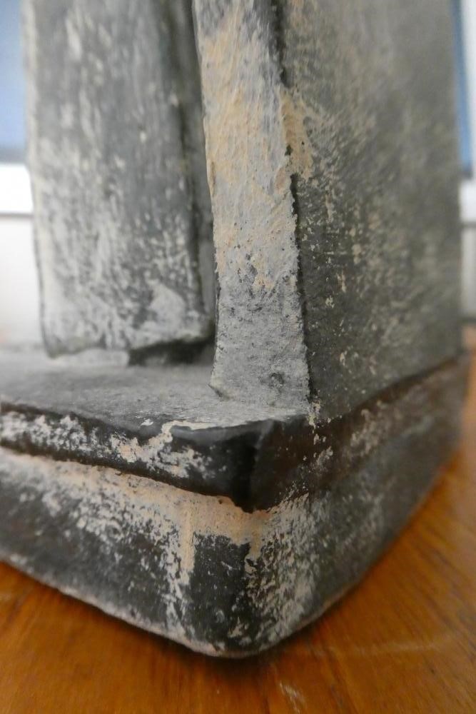 JOHN MALTBY (1936-2000) - a matt grey stoneware sculpture of two figures standing before a cut slab Image