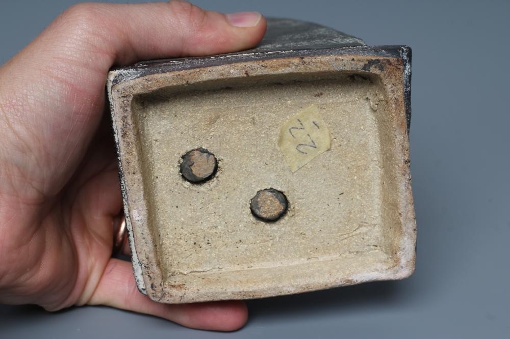 JOHN MALTBY (1936-2000) - a matt grey stoneware sculpture of two figures standing before a cut slab Image