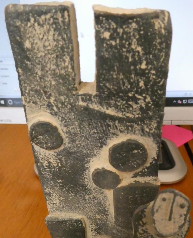 JOHN MALTBY (1936-2000) - a matt grey stoneware sculpture of two figures standing before a cut slab Image