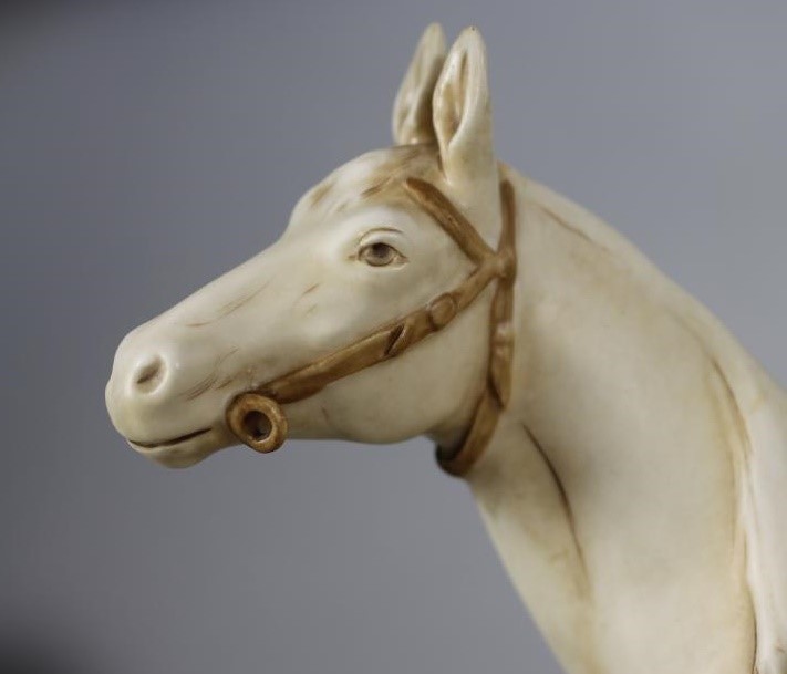 A ROYAL DUX PORCELAIN GROUP modelled as a young man wearing a green draped tunic seated astride a Image