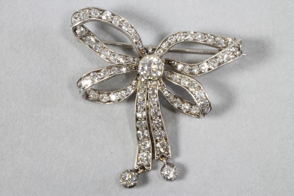 A VICTORIAN DIAMOND BOW BROOCH centred by a brilliant cut stone of approximately 0.60cts Image