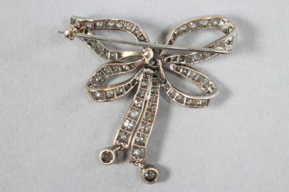 A VICTORIAN DIAMOND BOW BROOCH centred by a brilliant cut stone of approximately 0.60cts Image
